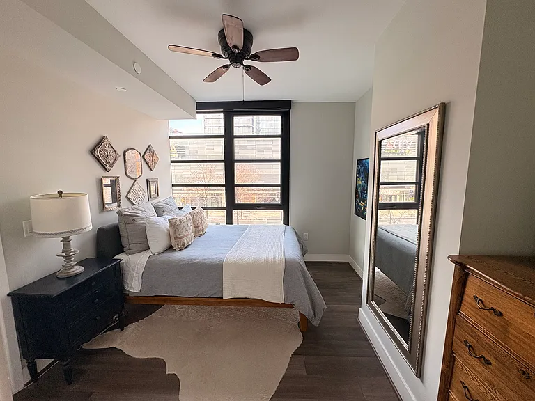 Primary bedroom with en suite bathroom, walk in closet complete with Elfa shelving, floor to ceiling windows with blackout shades and ceiling fan.