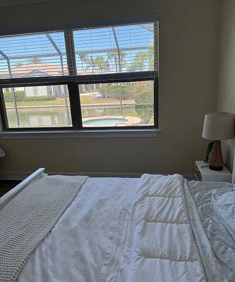 Master Bedroom with view of pool, lake, palm trees, and club house.