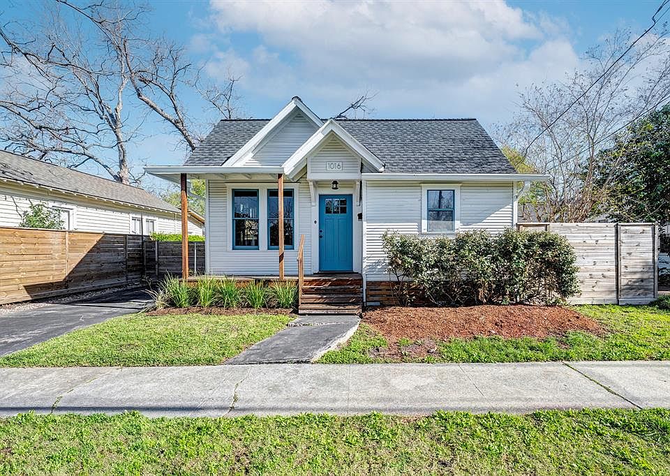Classic 1920s bungalow painted crisp white, featuring a welcoming blue door that adds a pop of color and timeless curb appeal.