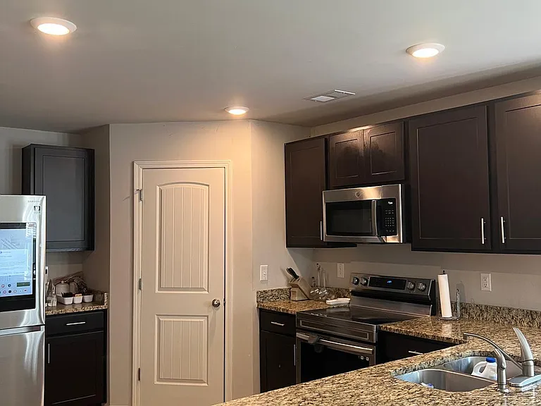 Functional kitchen with granite-look counters, ample dark cabinetry, and stainless-steel appliances including microwave and r