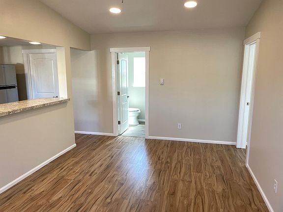 View from front door into spacious living room. Ceiling fan with vaulted roof above.