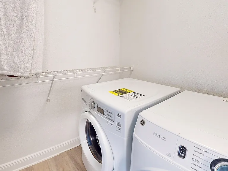 Modern laundry room featuring a sleek washer and dryer set against a bright, clean backdrop with convenient shelving.