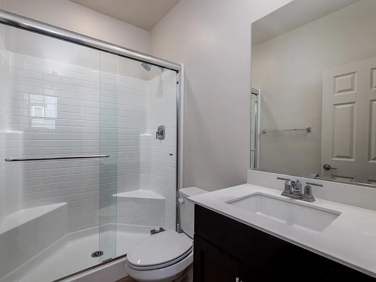 Ground-floor guest bathroom featuring a full bath with a glass-enclosed shower and modern vanity. Conveniently located to serve the downstairs bedroom, offering both comfort and privacy for guests or extended family.