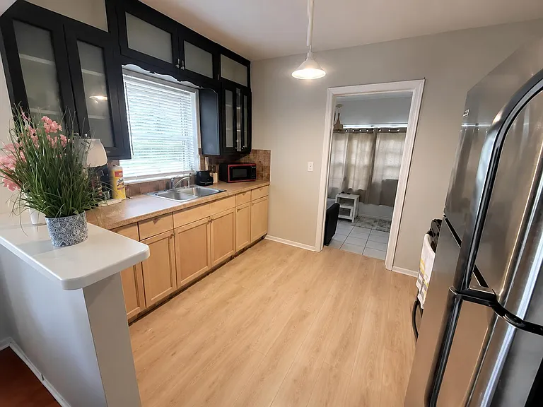 Functional kitchen with generous cabinet storage, double-basin sink, ample counter space, and full-size fridge.