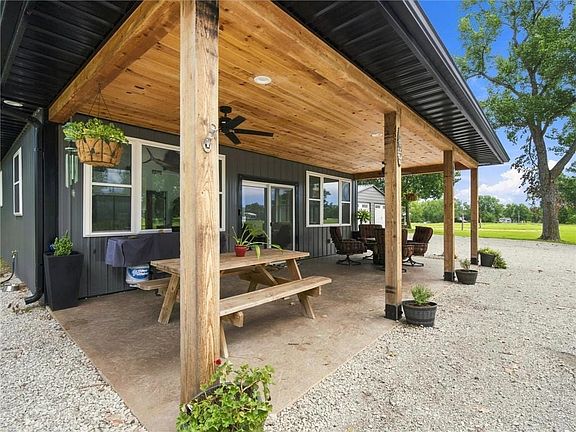 Spacious covered patio with wood-finish ceiling, exposed support beams, integrated lighting, and ceiling fan