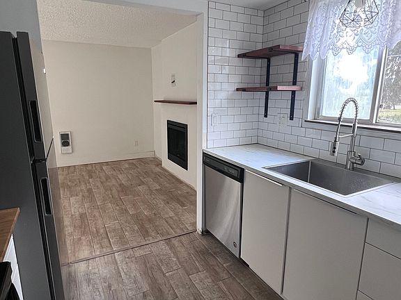 View of kitchen looking into living room, showing open shelving.