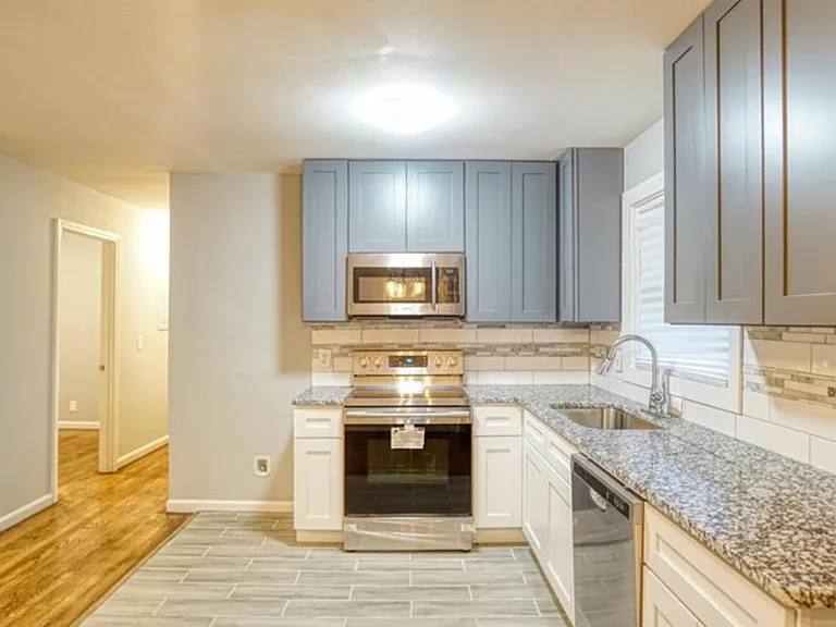 Updated kitchen with granite counters, stainless appliances, ample cabinetry, and a window over the sink.