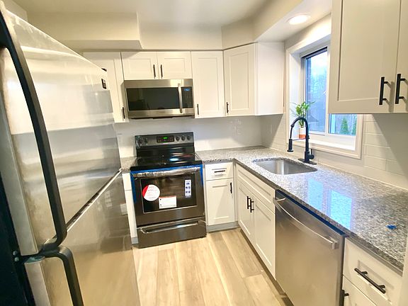 Renovated kitchen with white shaker cabinets, stainless steel appliances and granite countertops