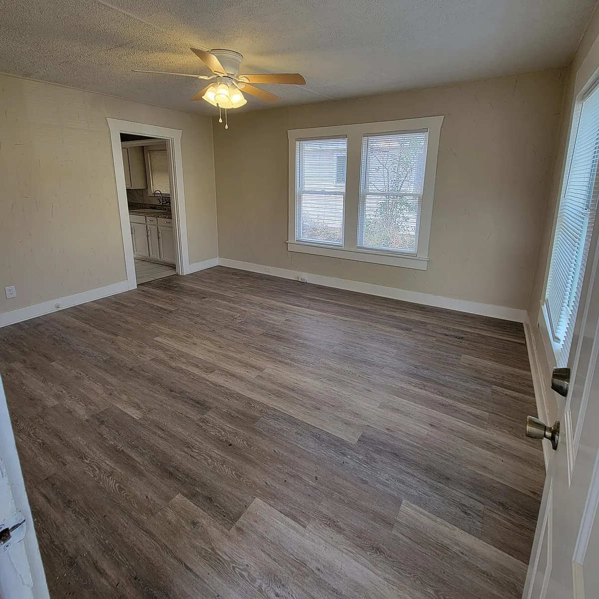 Living room from the front door with all new flooring, paint, ceiling fan and mini blinds - 5517 Pershing Ave