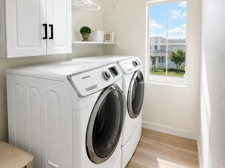 Dedicated laundry room with front-load washer and dryer, overhead cabinets, and a shelf with hanging rod for storage.