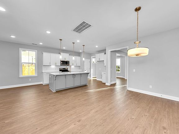Spacious gathering room with elegant engineered wood flooring and a timeless light pendant.