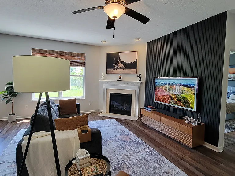 Sleek slat panel accent wall in fireplace/living area. Say goodbye to tangled wires_the home features cord-concealed, flush-mounted TV setups, allowing for a clean, gallery-like look in your primary living spaces.