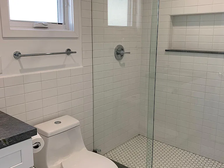 Tiled bathroom with granite counters.