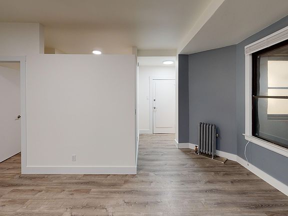 Sunlit room with a large window and wood-like flooring