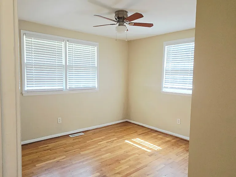 Master bedroom with ceiling fan/light and natural hardwood floors.