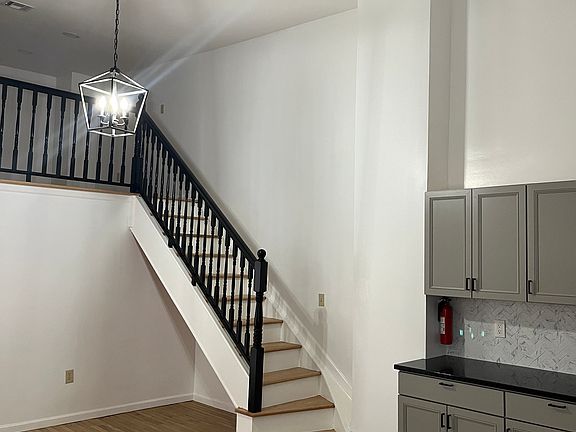 loft stairs leads to living room area, high ceilings in kitchen/dining
