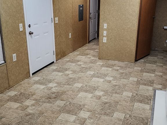 View of front door from the kitchen. Bathroom is to the far right. The hallway leads to the back bedroom with bunkbeds