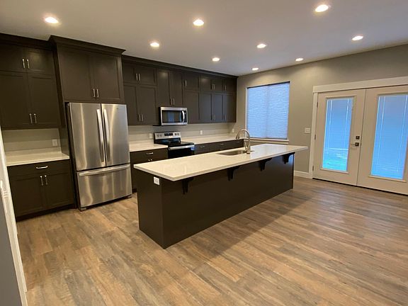 Spacious kitchen w/ custom built cabinets, stainless steel appliances, and quartz countertops.