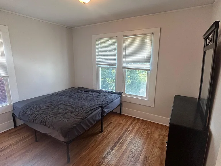 Private bedroom with hardwood floors, a large window, and space for a full bed plus dresser or work surface.