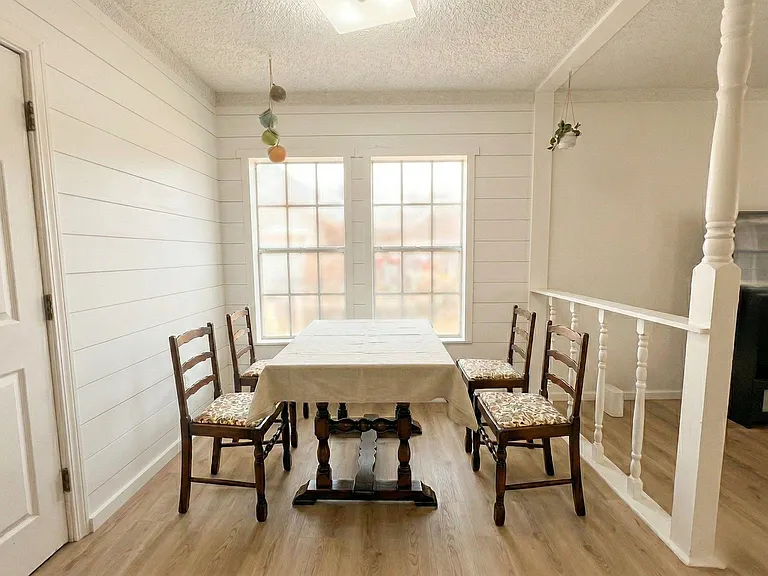 Dining area with a table for four, shiplap-style walls, and large windows that provide natural light for everyday meals.