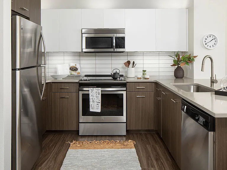Apartment Kitchen with Stainless Steel Appliances, quartz counters and wood floors.