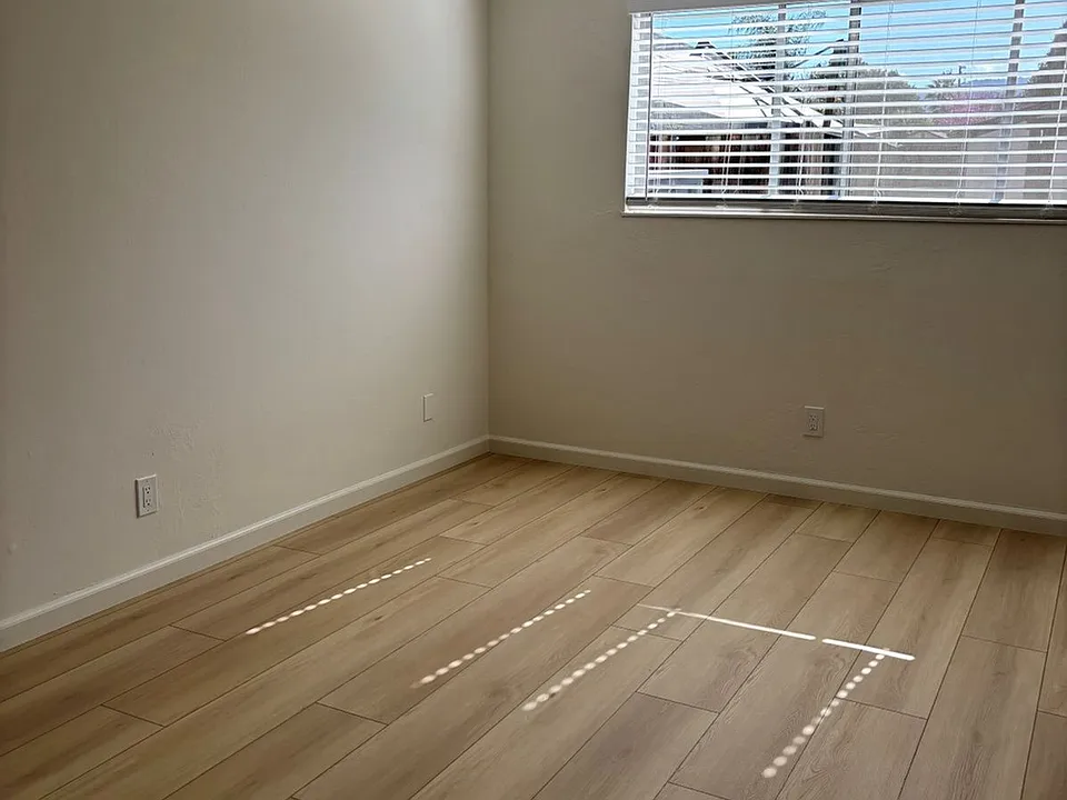 A generously sized bedroom with mirrored closet doors that add brightness and a sense of expanded space.