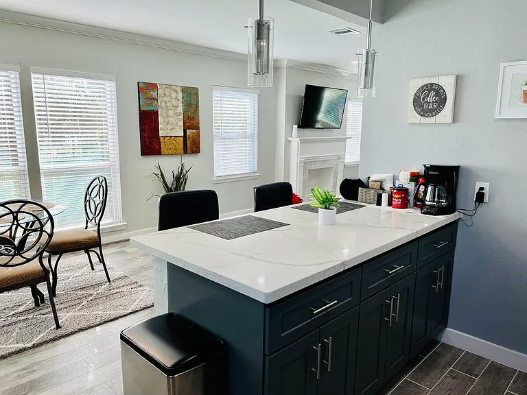 Spacious kitchen island with stone-look counters, ample cabinet storage, and adjacent dining area with large windows.