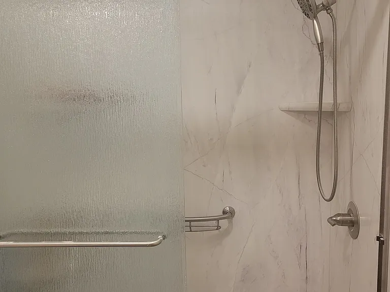 Updated bathroom with storage cabinet with soft-close doors and room to hold both bath towels and personal care items. Dual soap/shampoo shelves in the shower.