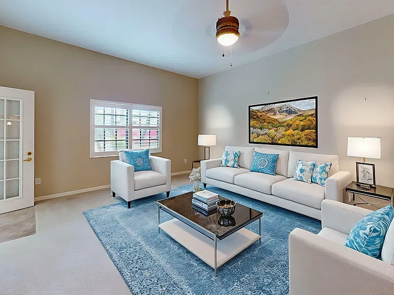 Elegant living room with plush white seating, vibrant blue accents, and a modern glass coffee table, creating a welcoming ambiance.