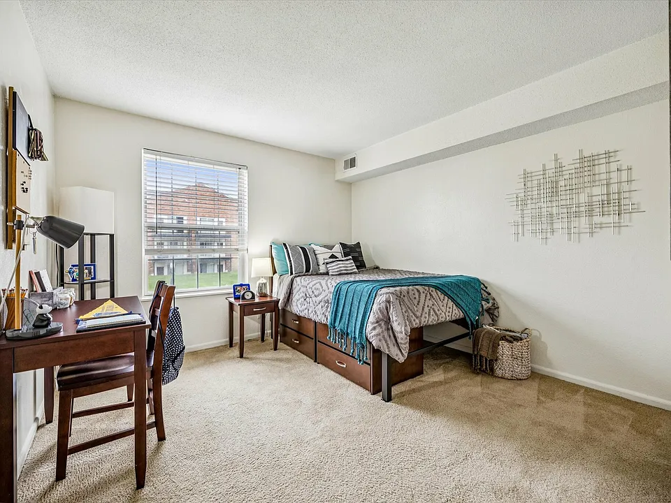 Relax in a cozy bedroom with a study space and modern decor at University Hills Apartments near the University of Toledo.