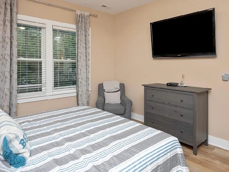 master bedroom with own TV, fan, chair, connected to master bathroom