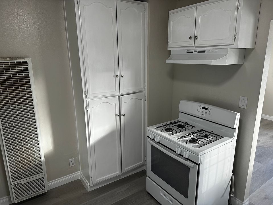 Kitchen view looking out towards living room. Stove and pantry.