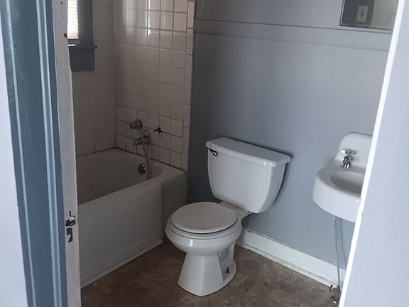 Bathroom- has toilet, bathtub, and sink, with storage cabinets behind the door.