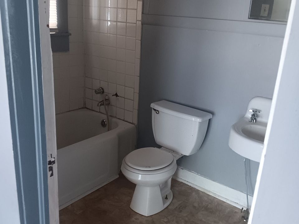 Bathroom- has toilet, bathtub, and sink, with storage cabinets behind the door.