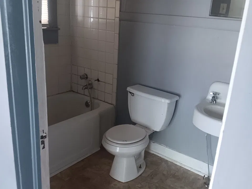 Bathroom- has toilet, bathtub, and sink, with storage cabinets behind the door.