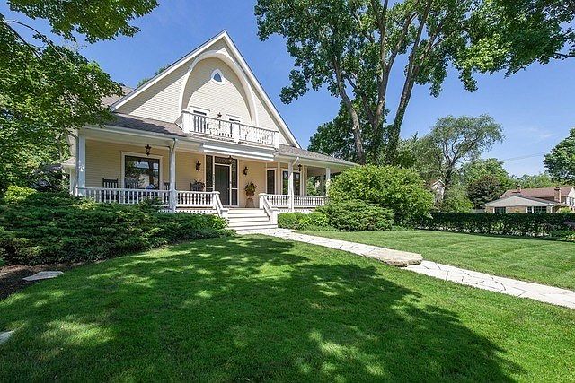 Impressive architecture inspired by a Wisconsin Farmhouse with a large lawn and plush greenery.