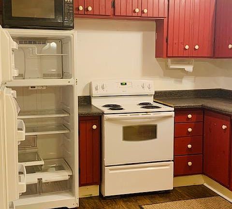 Kitchen has electric stove and painted pine cabinets.