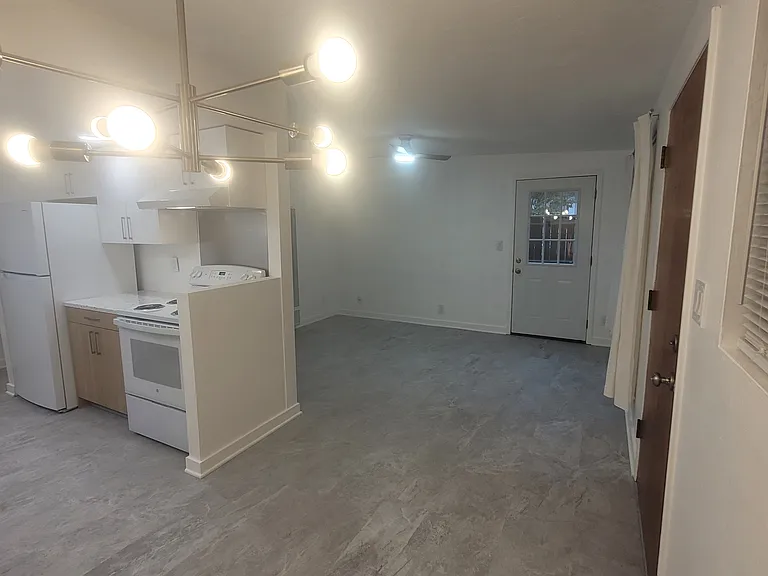 View from dining space into living room and galley kitchen. Back door to deck and private yard is off of the living room.