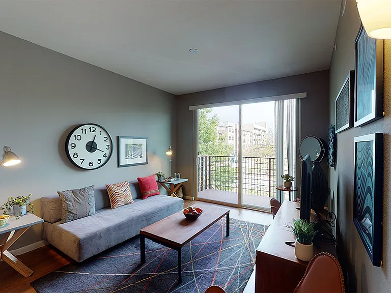Apartment living room with wood-style flooring and balcony or patio in select homes.