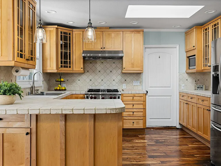 Heart of the home this chef-inspired kitchen features warm wood cabinetry, a premium gas range, and a bright skylight that fills the space with natural light.