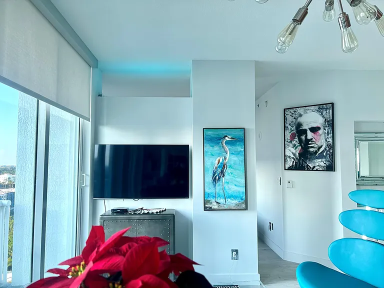 Living area with leather dual recliner couch, glass coffee table, smart TV, buble chair, LED multicolor lights and remote shades.