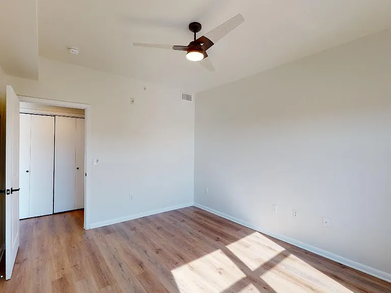 Spacious apartment bedroom with wood-style flooring.