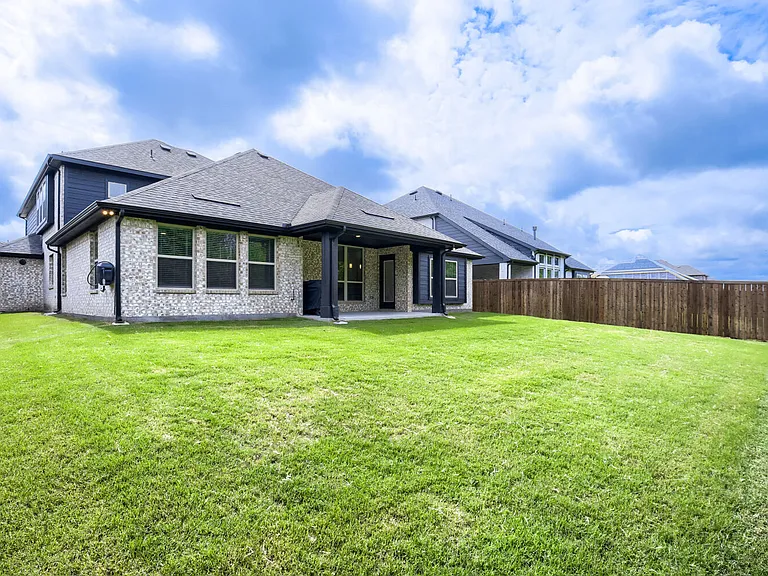 Expansive green lawn with a two-story residence featuring light brick and dark siding