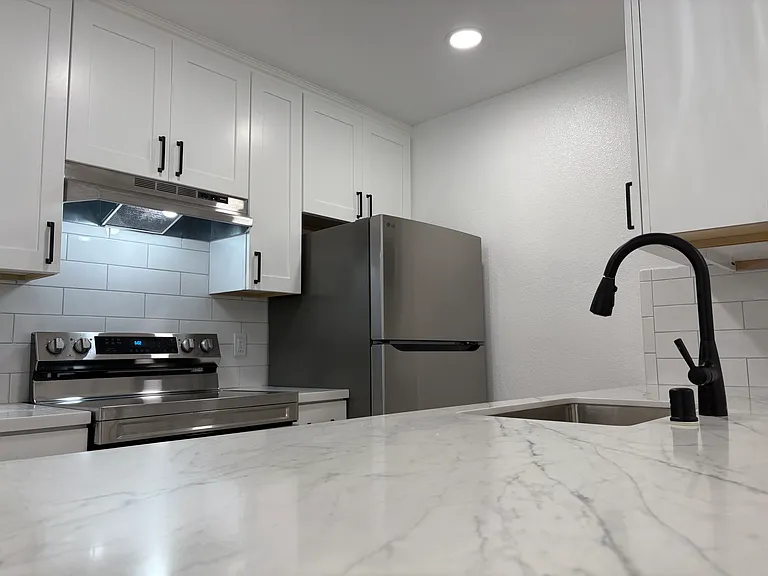 Remodeled kitchen with updated stainless steel appliances, tiled backsplash, elegant cabinetry and countertops