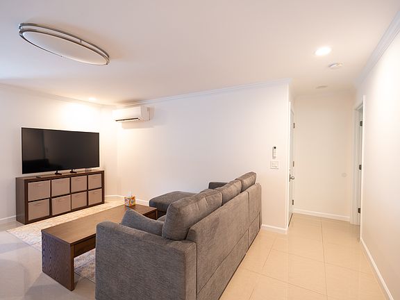 Living room with all new furniture, pull out sectional sofa and coffee table converts to a TV stand- New 65 inch Samsung- Entry to garage and bedroom 2