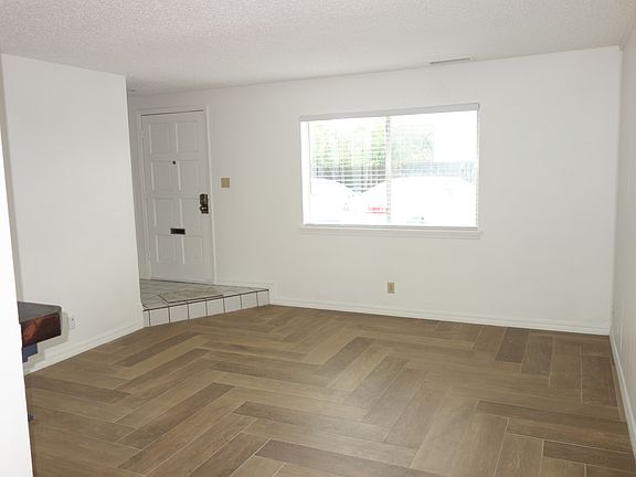 Living room view with Entry door on the left and large front window with screen and blinds