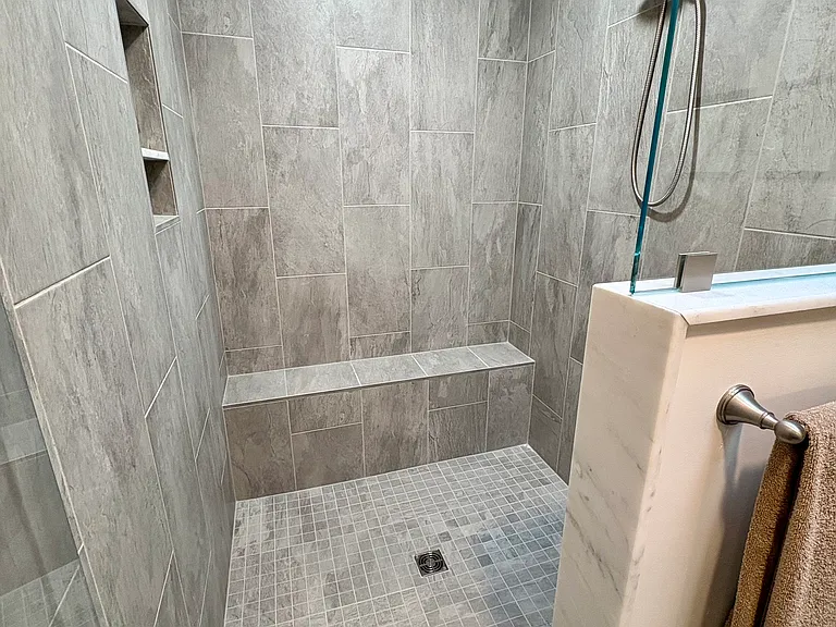 Huge tile shower features a built in bench and magnetic shower head that can convert to a handheld sprayer. Tall glass door and window hold in the warmth for an incredibly luxurious shower experience!
