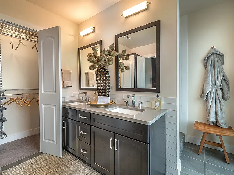 Bathroom with large closets, dark cabinetry and framed mirrors