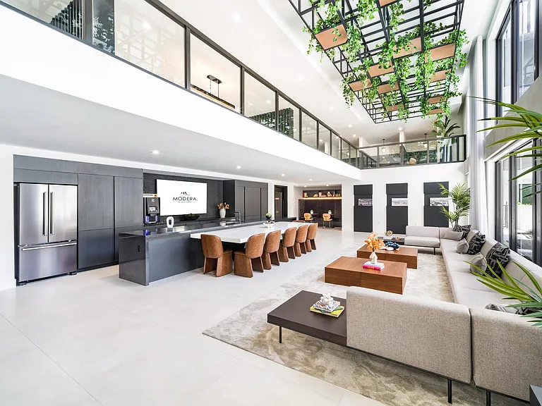 Grand clubroom with soaring ceilings, an oversized gathering island, and flexible seating areas designed for hosting, working, and unwinding.