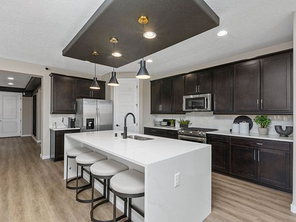 Beautiful brand new kitchen shown with a modern look of brown cabinetry, white countertops, and blac